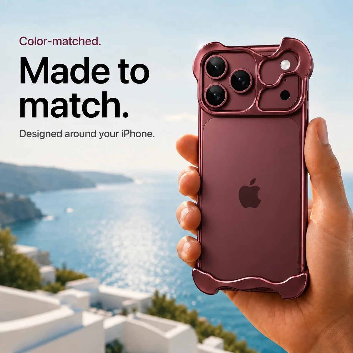 Burgundy sculpted metal phone case held above a coastal background #color_Burgundy