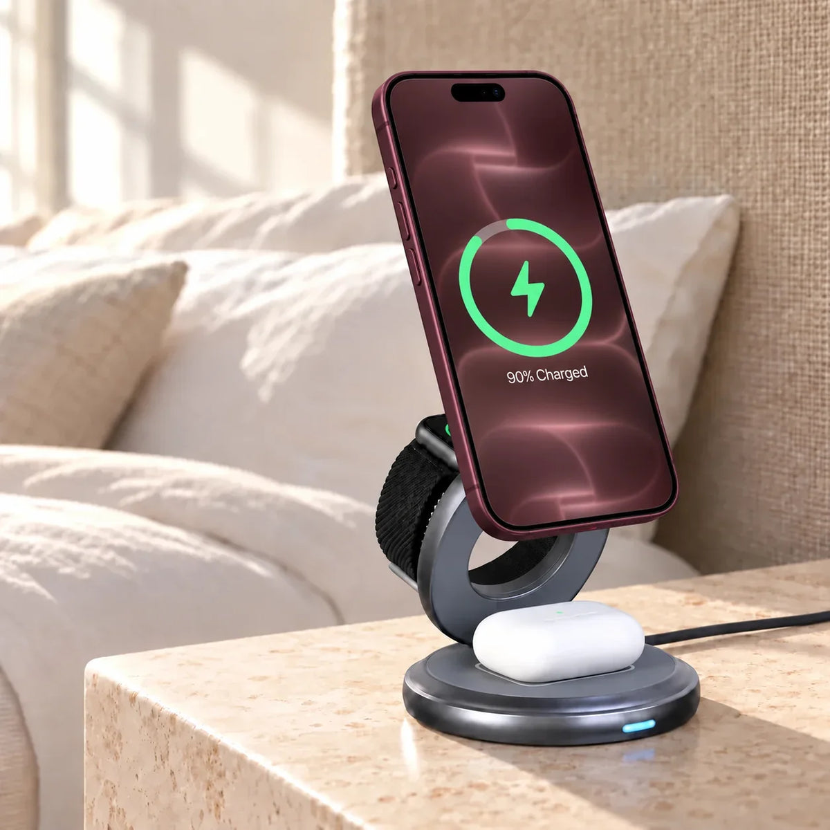 Gray wireless charging stand with a phone and white earbud case on a bedside table.