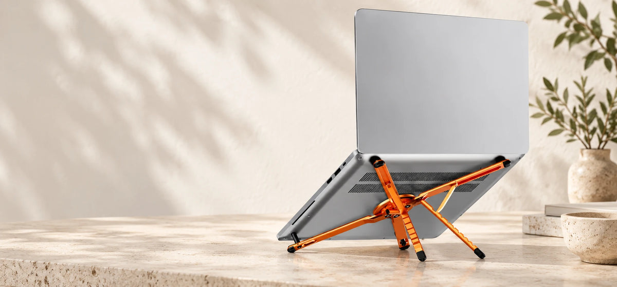 Orange aluminum folding stand supporting an open silver laptop.